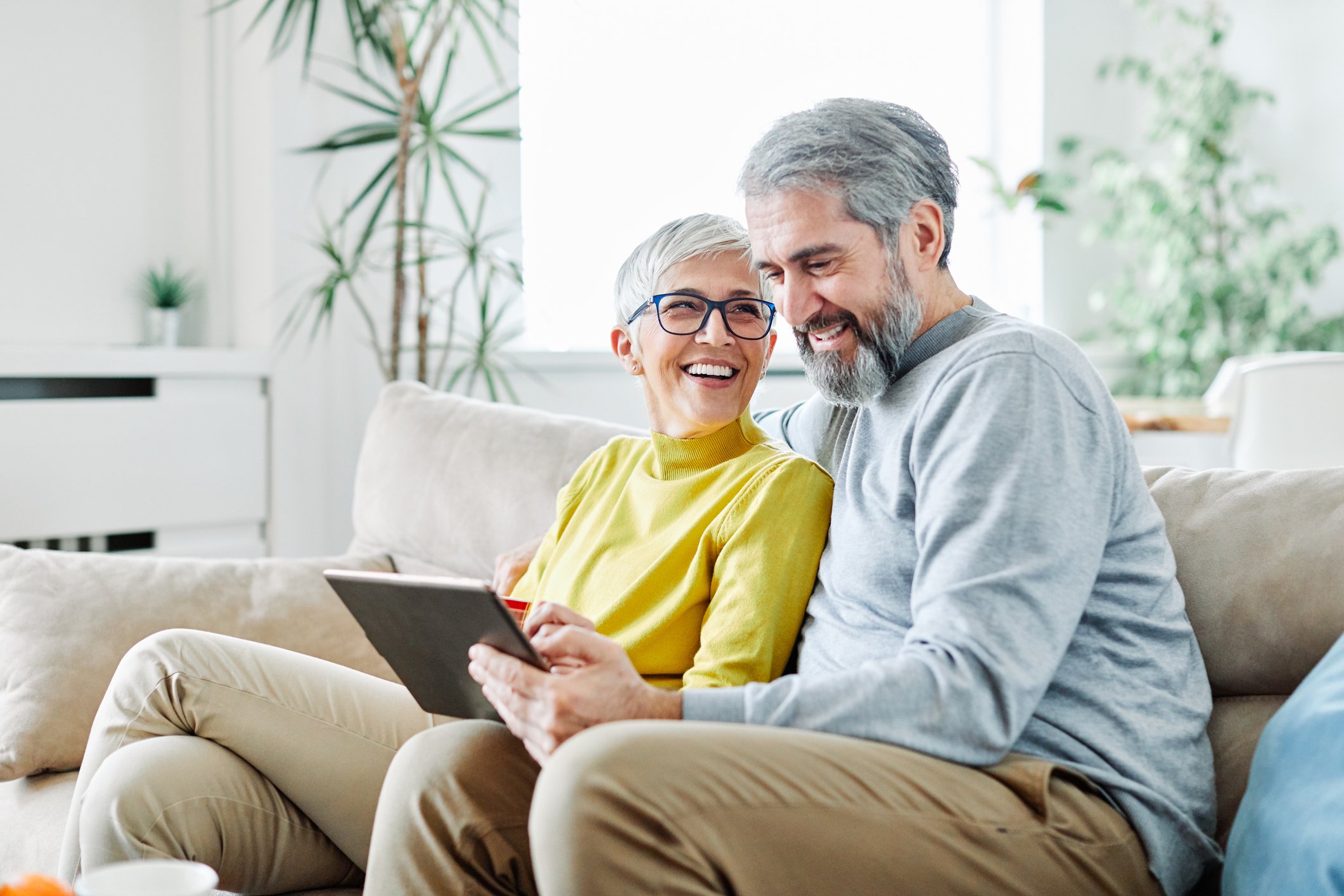Older couple smiling and looking at tablet computer