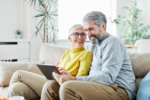 Older couple smiling and looking at tablet computer