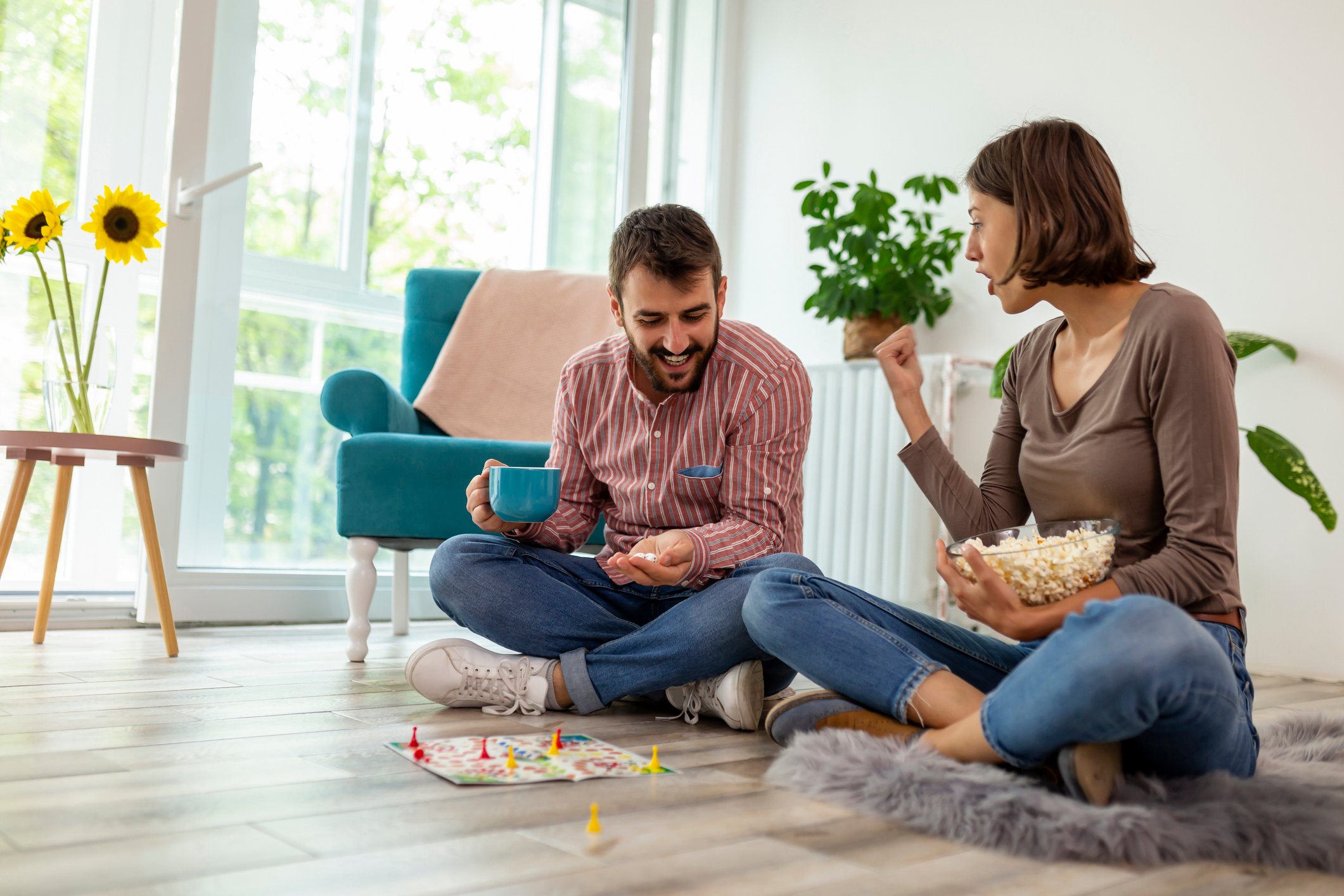 A man and woman sitting on a floor, playing a board game.
