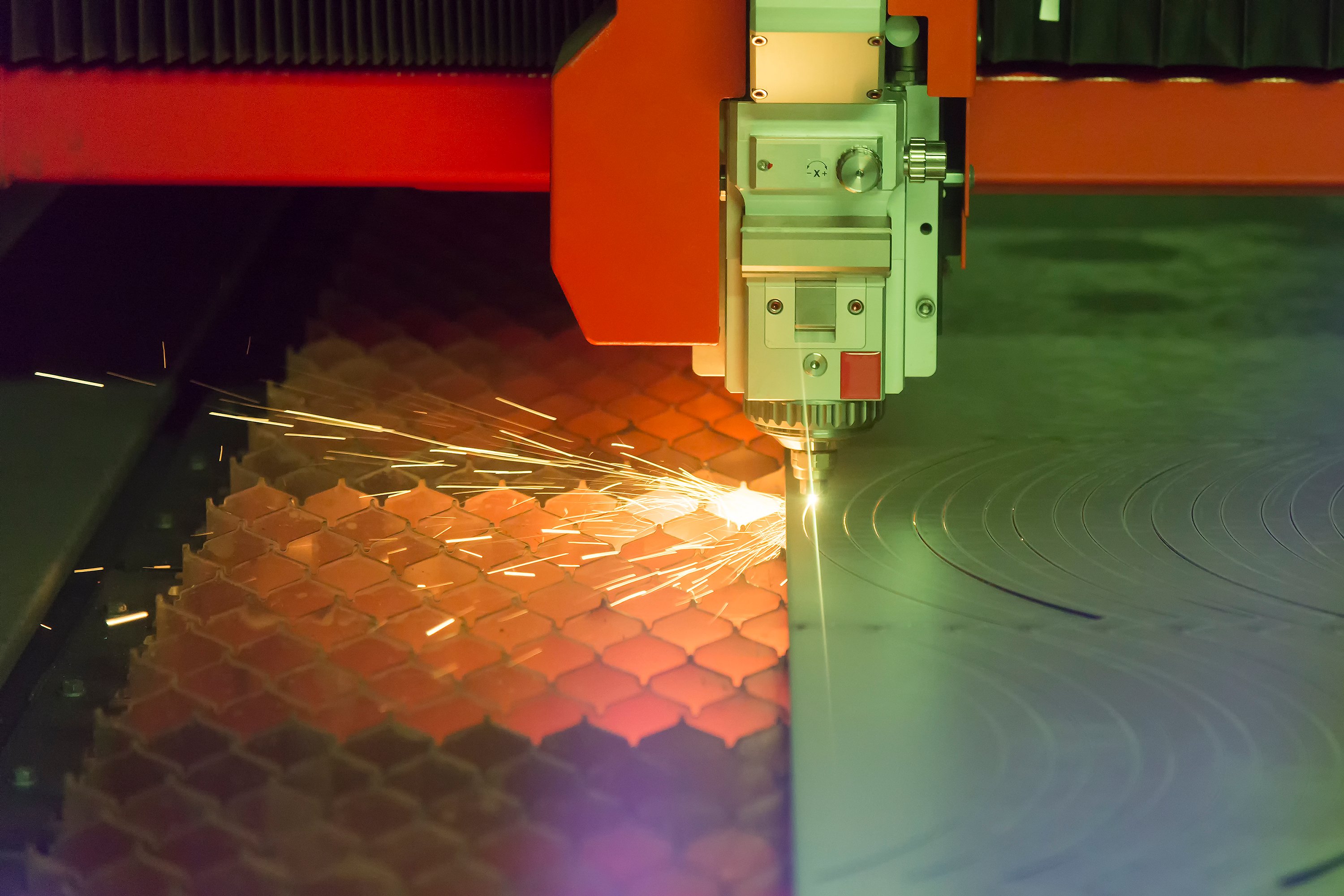 Photo of an industrial  fiber laser cutting through a sheet of plate steel.