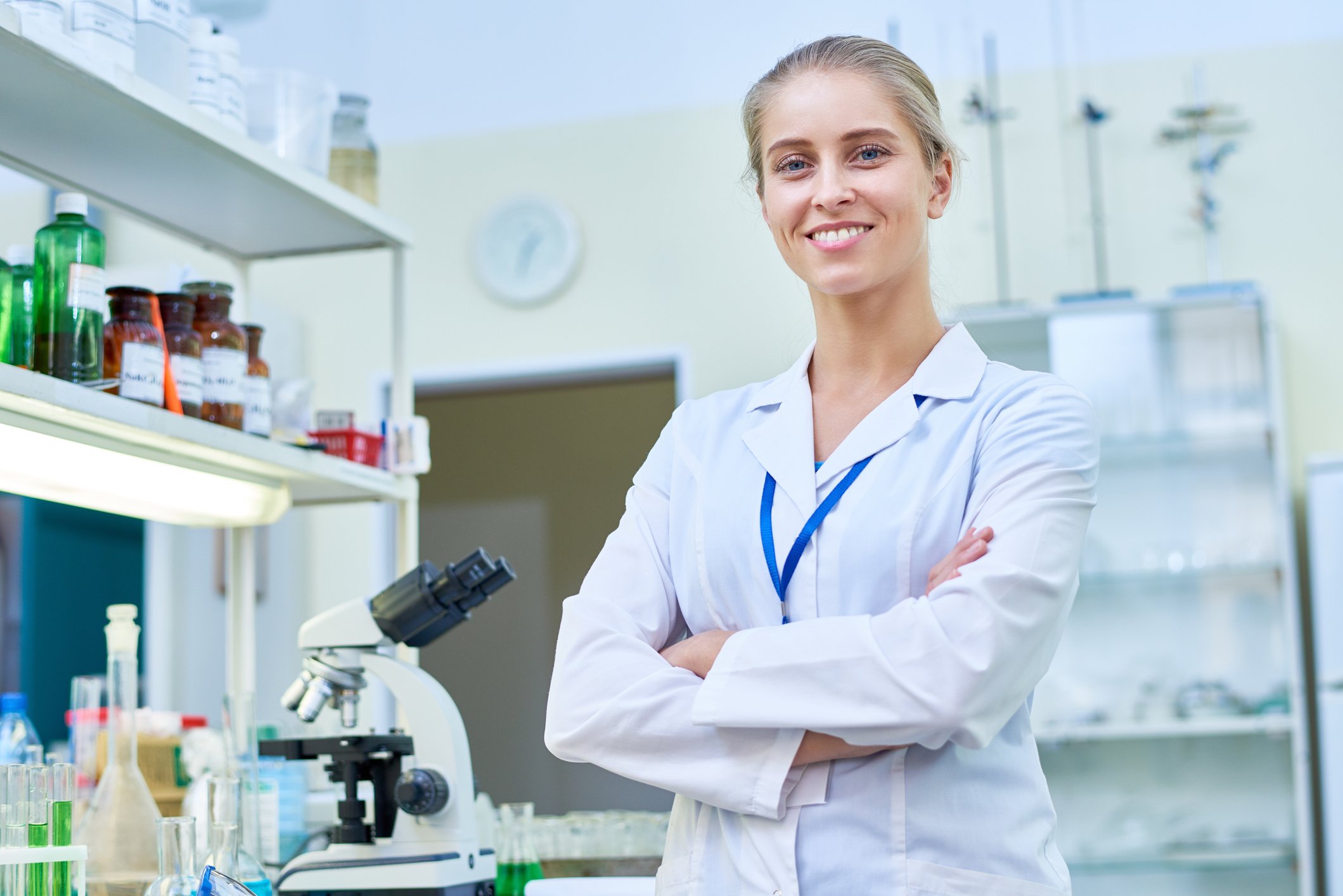 Smiling female pharmacist in pharmacy with her arms crossed.