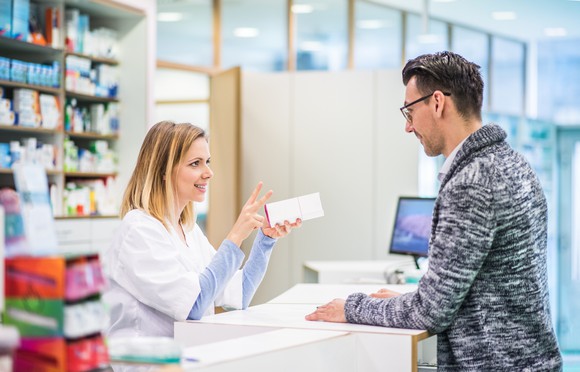 A pharmacist speaks to a customer at pharmacy counter.