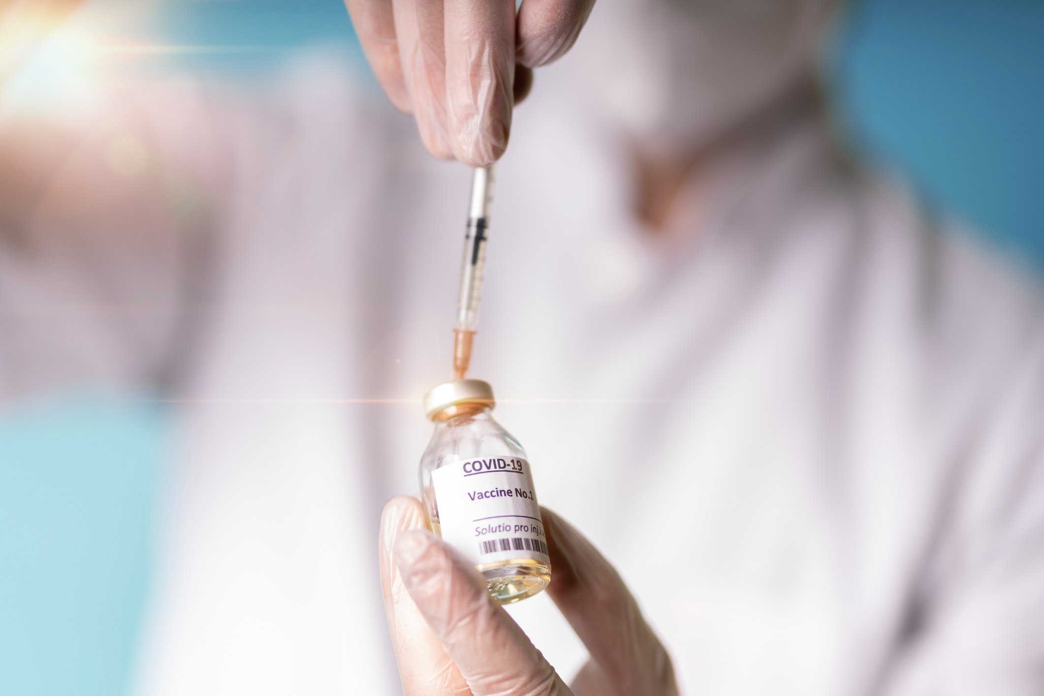 A doctor fills a syringe with a COVID-19 vaccine in a vial.