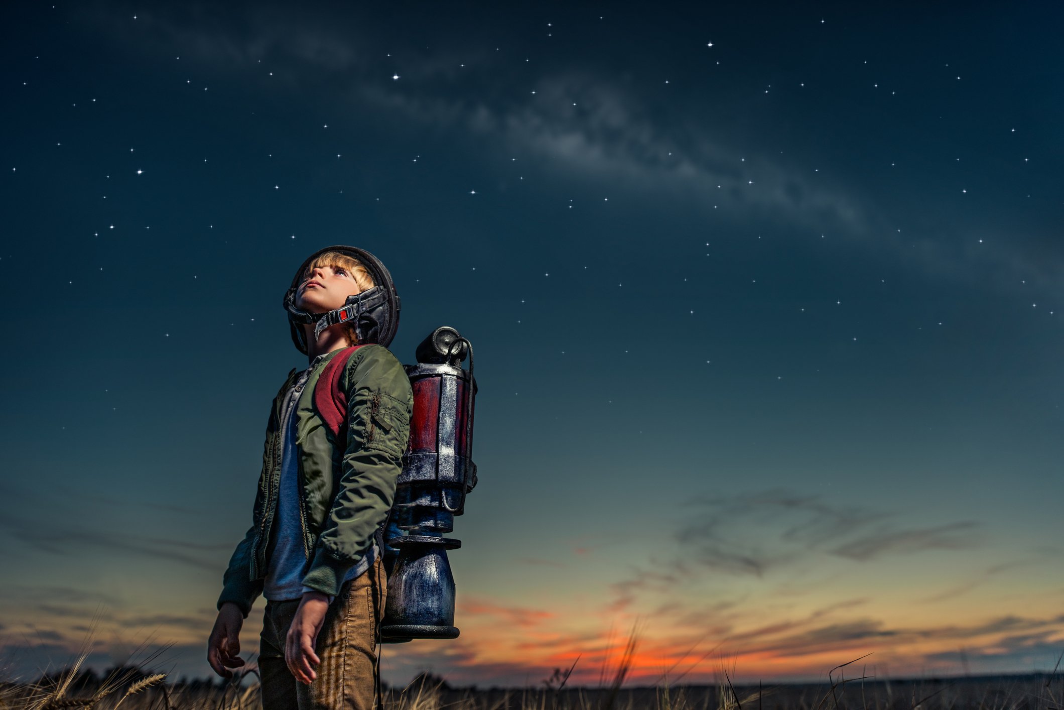 Boy in jetpack stares  at the sky.