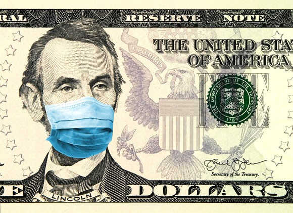 Portrait of Lincoln wearing a mask printed on a five dollar bill. 