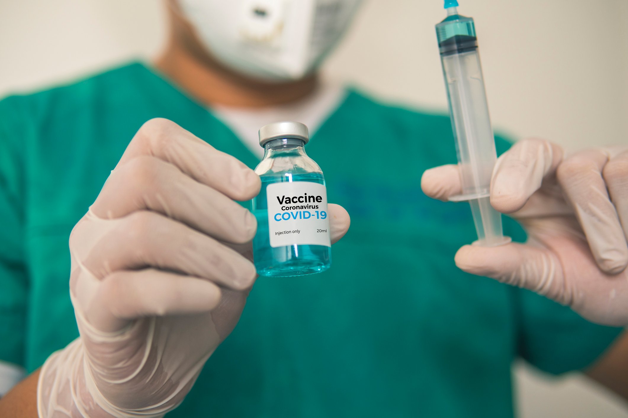A researcher holds up a dose of vaccine and a syringe.