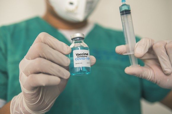 A researcher holds up a dose of vaccine and a syringe.
