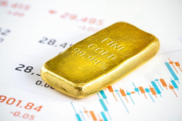 A gold bar lies on a financial chart.