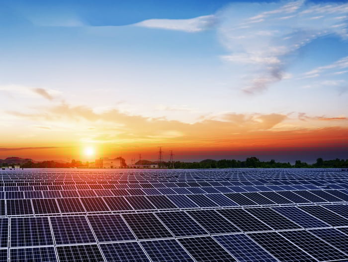Solar panels under a blue sky at sunset.