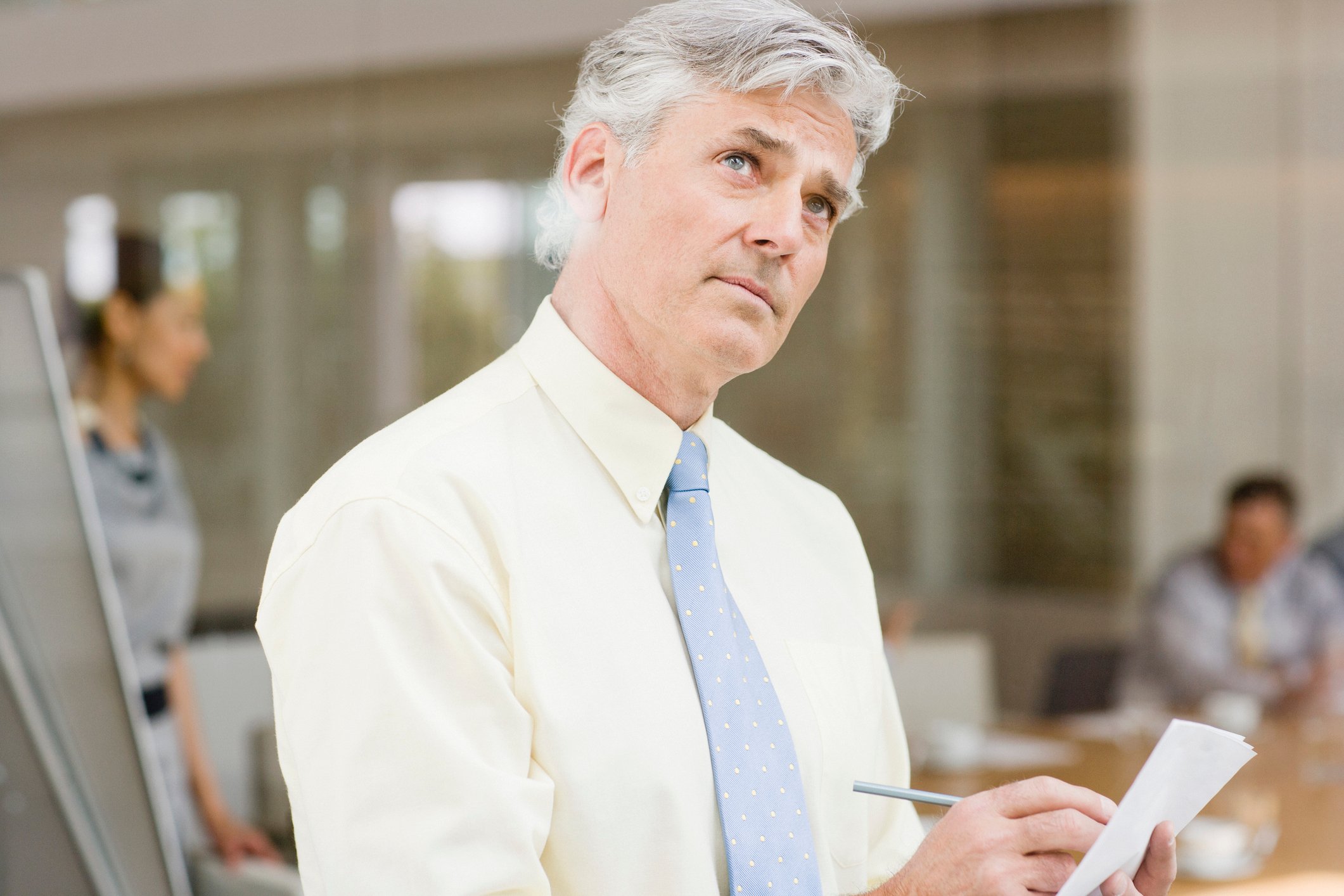 Older man in dress shirt and tie writing on piece of paper