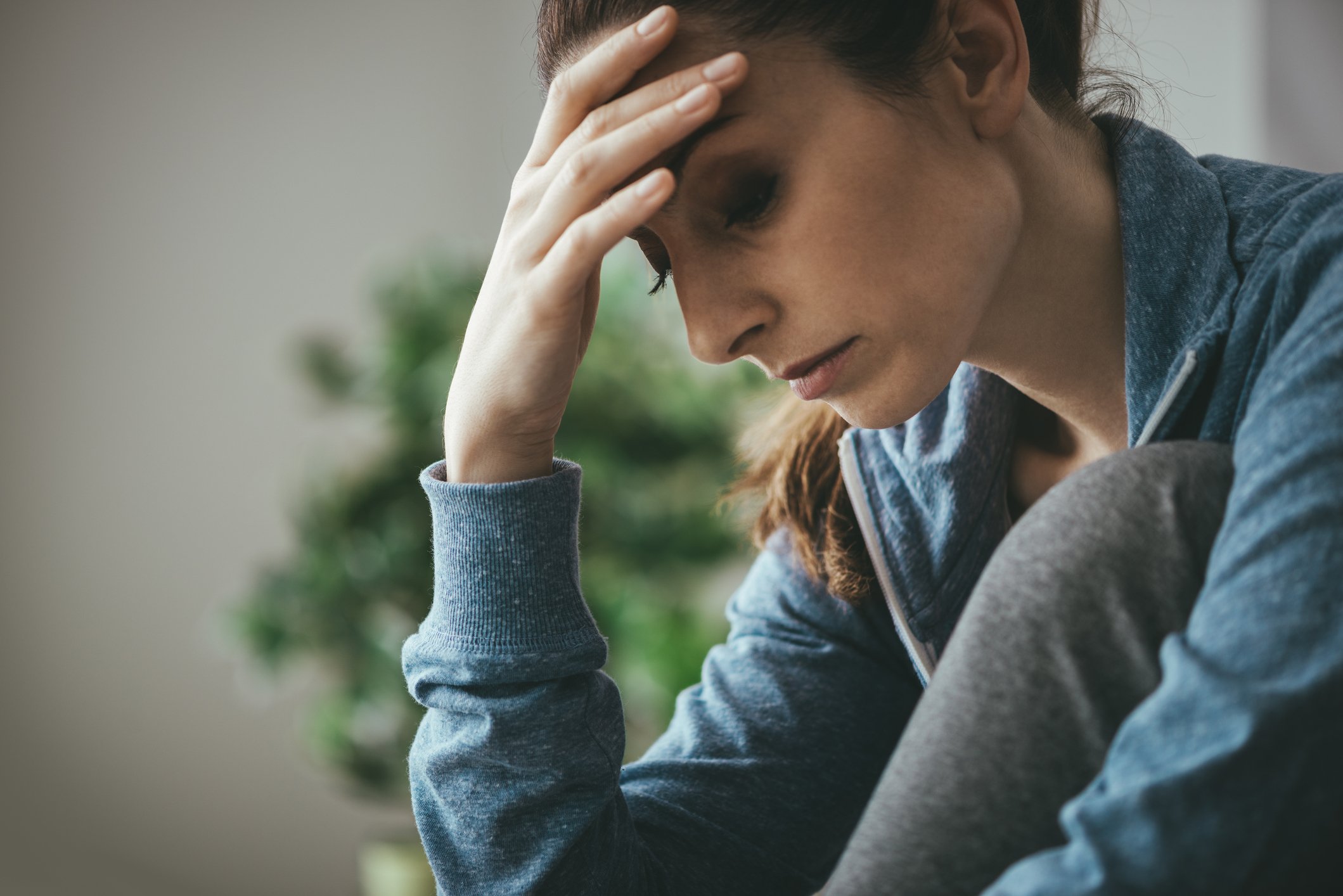 Stressed out woman resting her forehead on her hand.