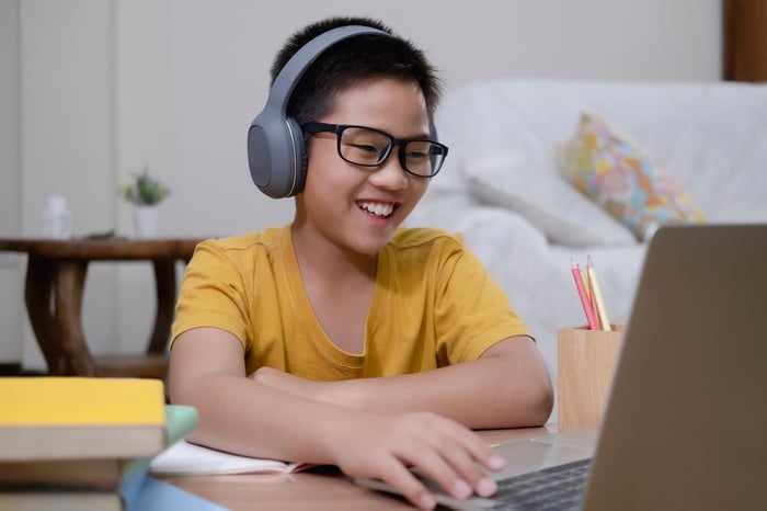 A young boy studies on a laptop.