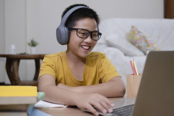 A young boy studies on a laptop.