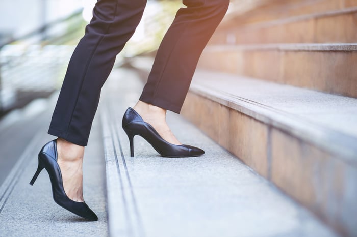 Person wearing high heels walking up the outdoor steps of a building