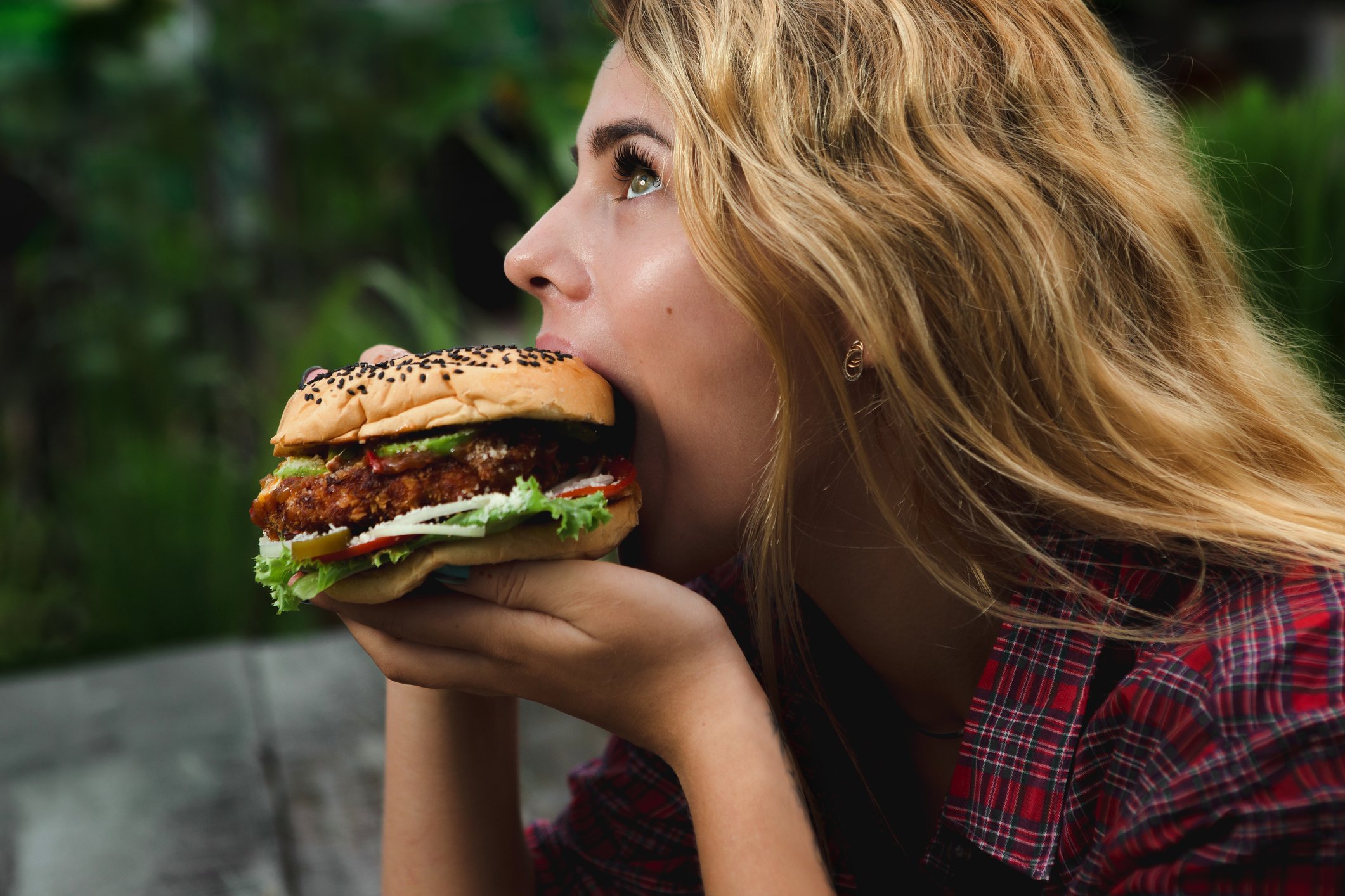 A young woman takes a big bite of a burger. 