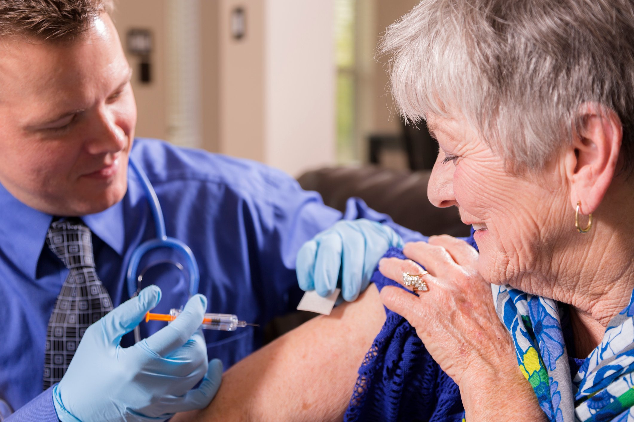 A physician administering a vaccine to a senior citizen. 
