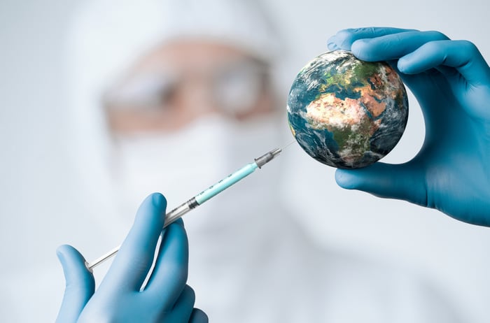 A researcher injecting a vaccine into a minature Earth.