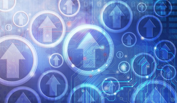 A rendering of many arrows pointing up on top of a blue circuit-board pattern.