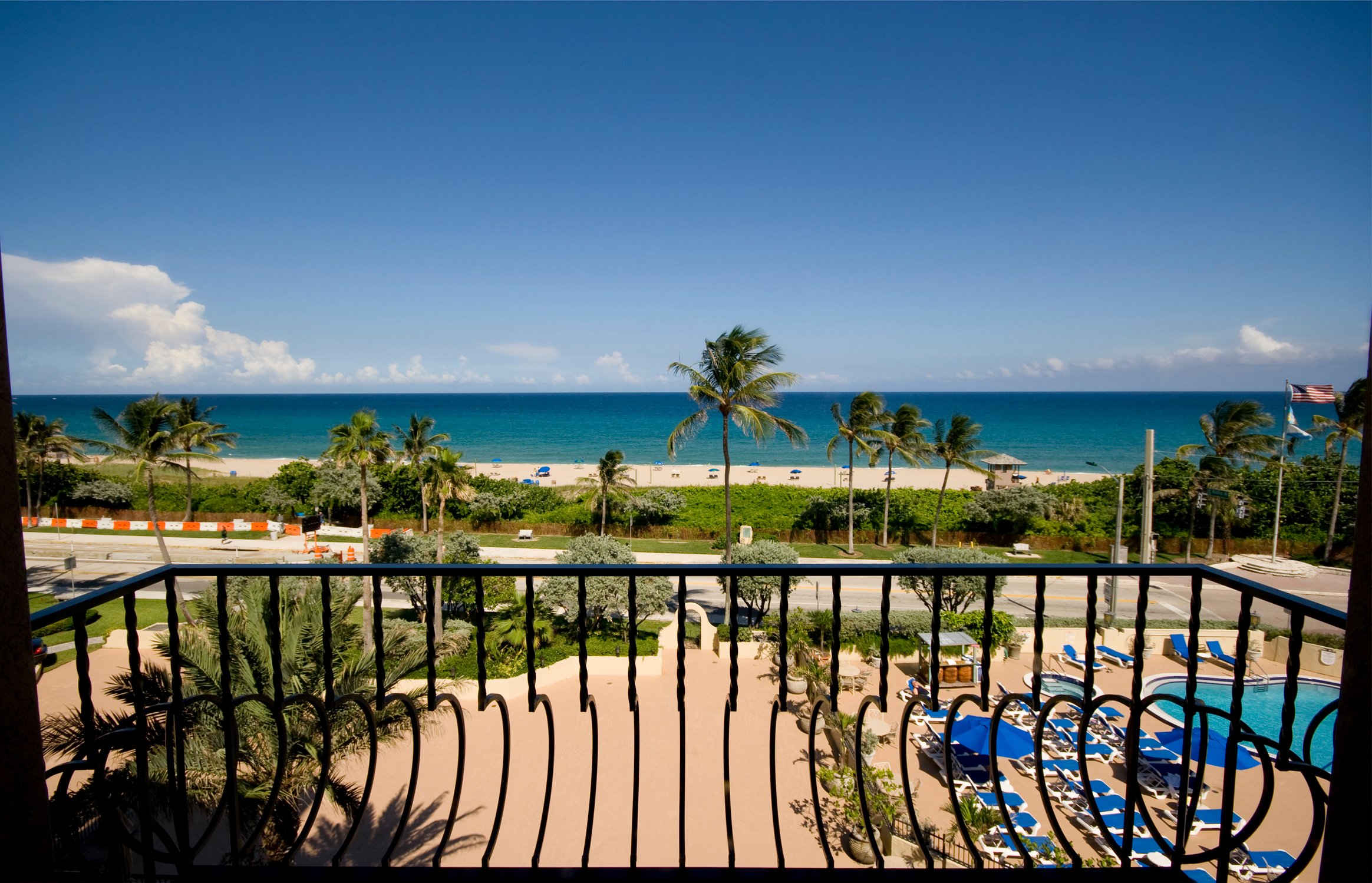 view of ocean with palm trees from hotel balcony