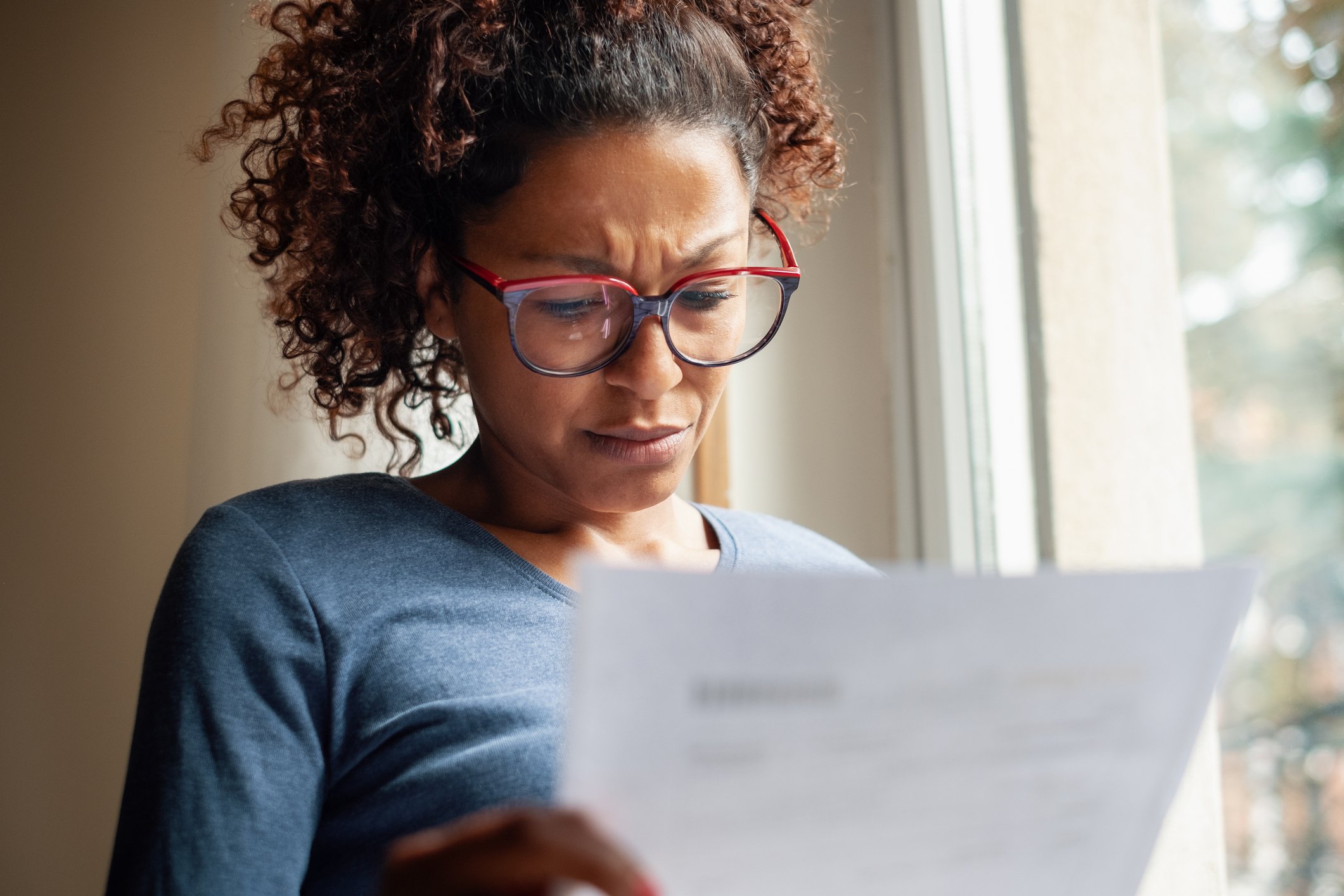 A women consults a bill with a pained expression.