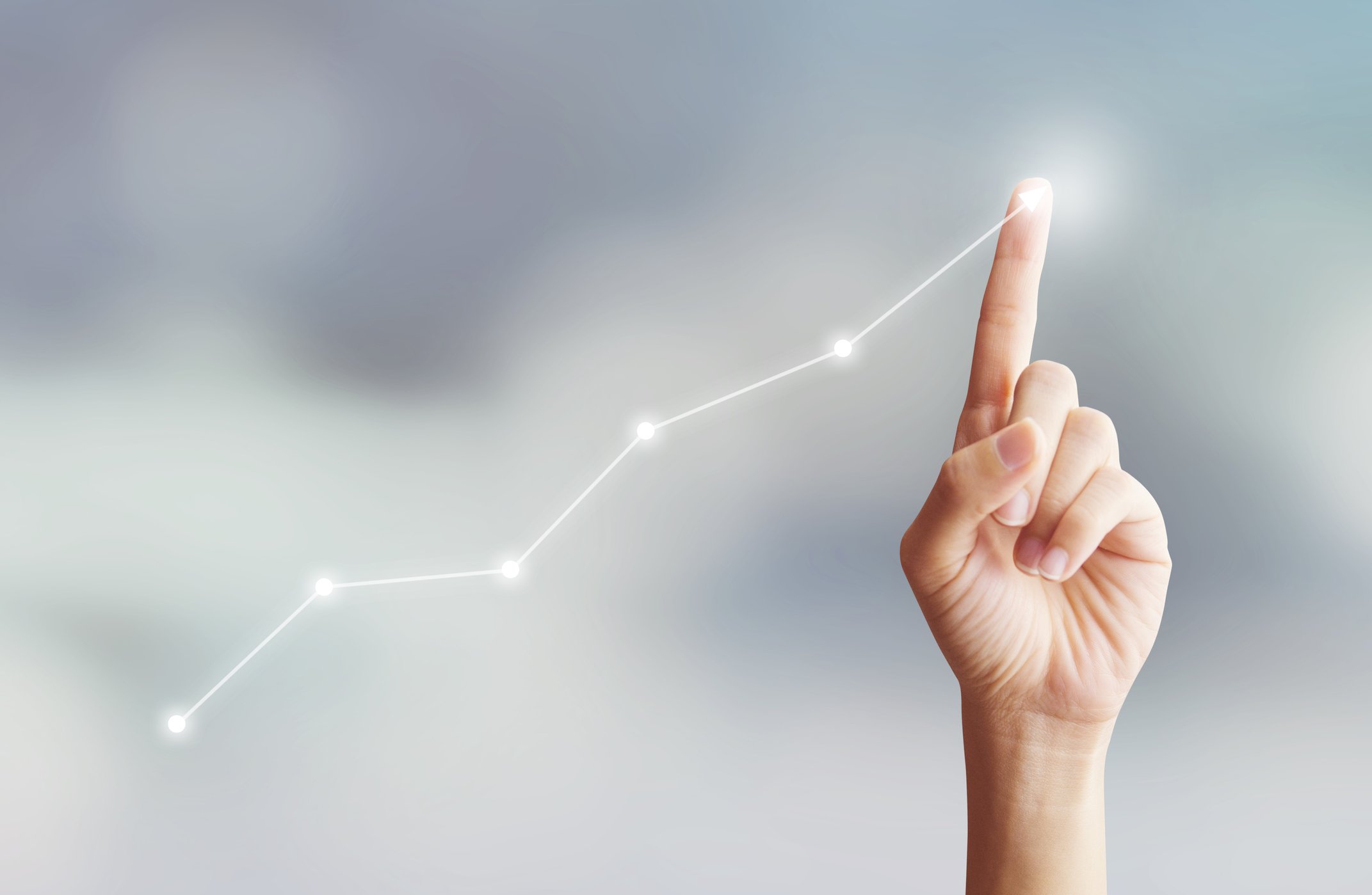 A finger traces an upward-trending line, suggestive of a rising stock chart.