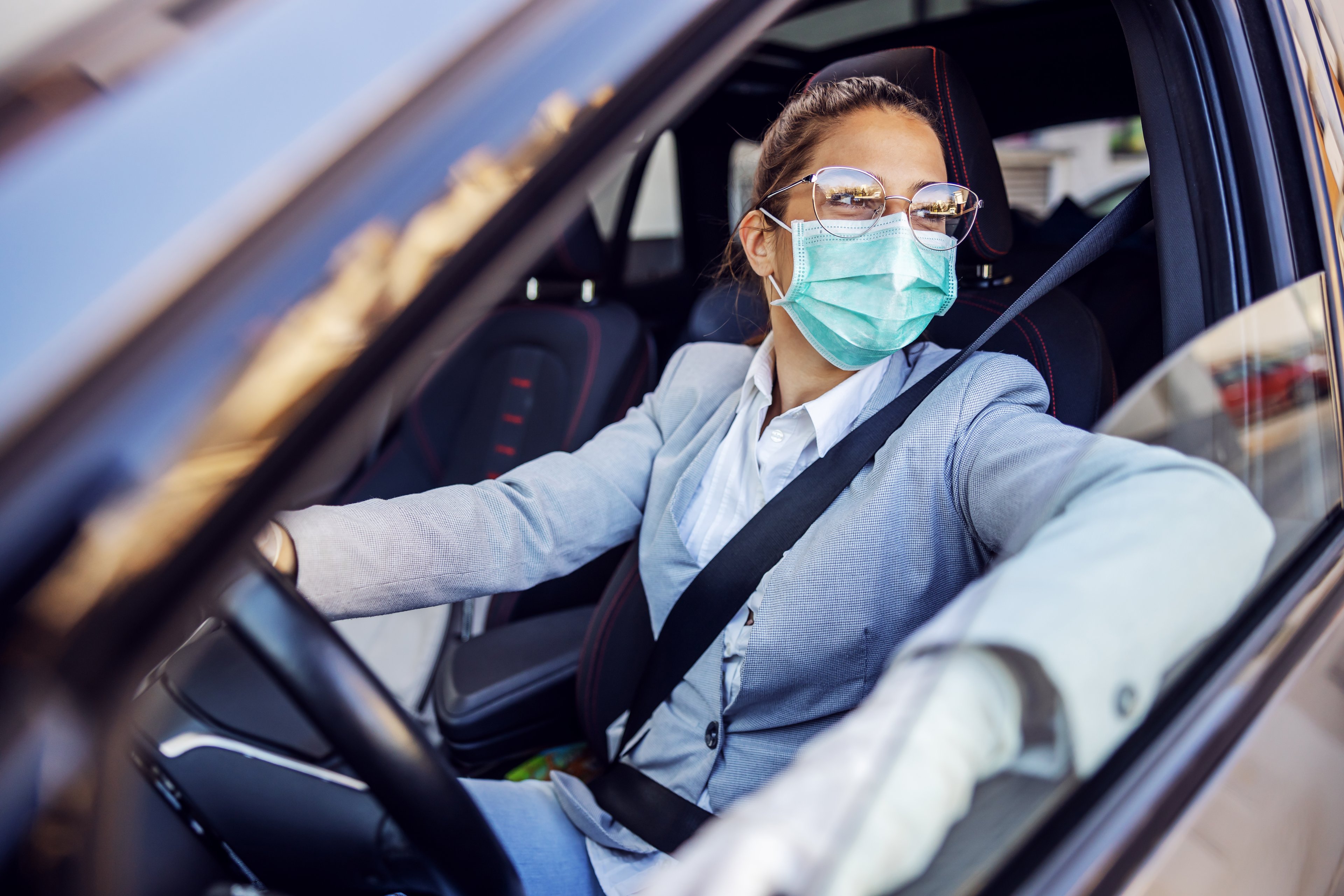 Businesswoman wearing mask while looking out the car window. 