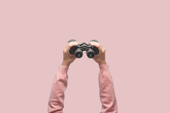Hands holding up a pair of binoculars.
