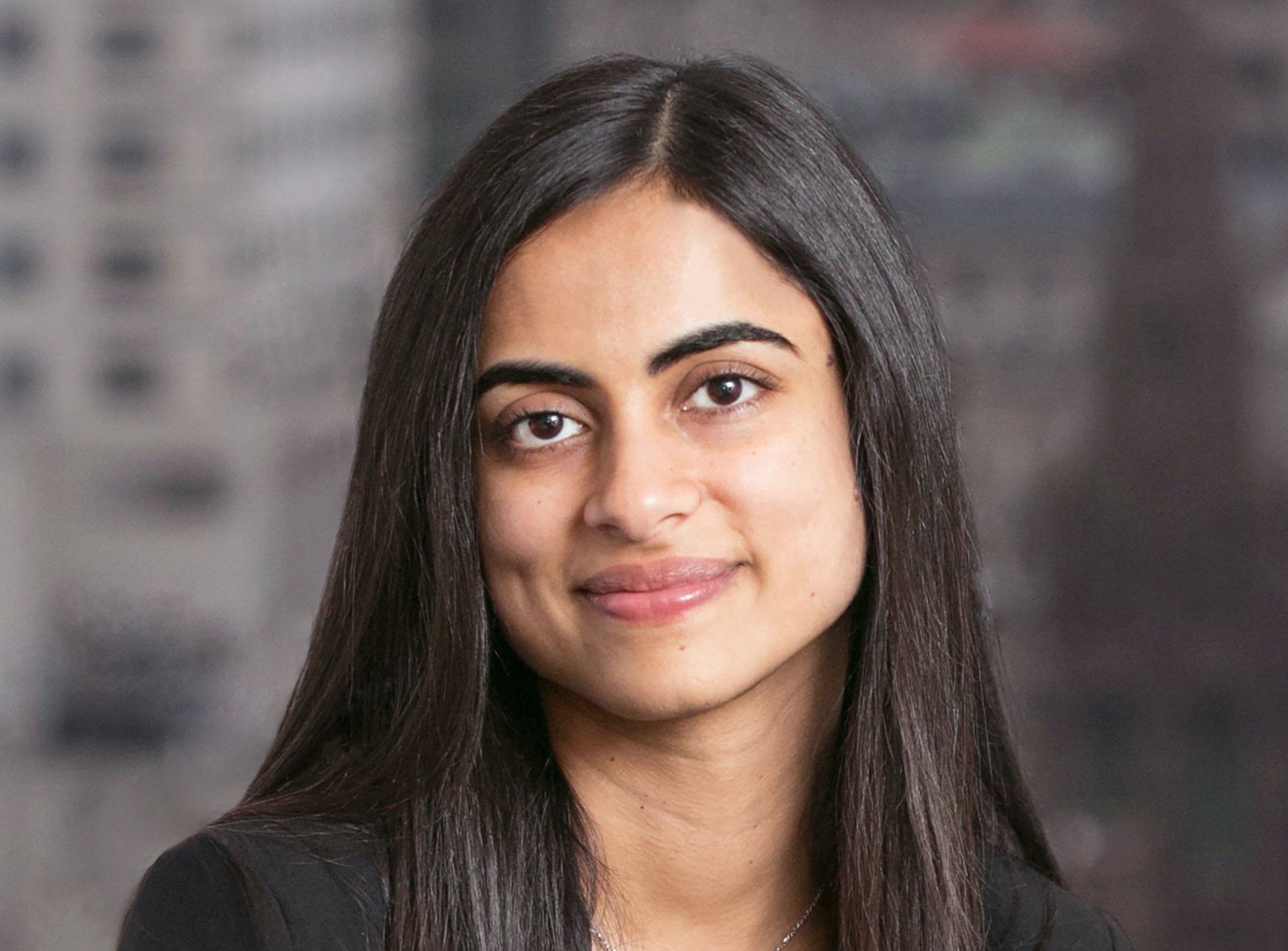 Dhivya Suryadevara is shown seated before a window in  a GM corporate photo. 