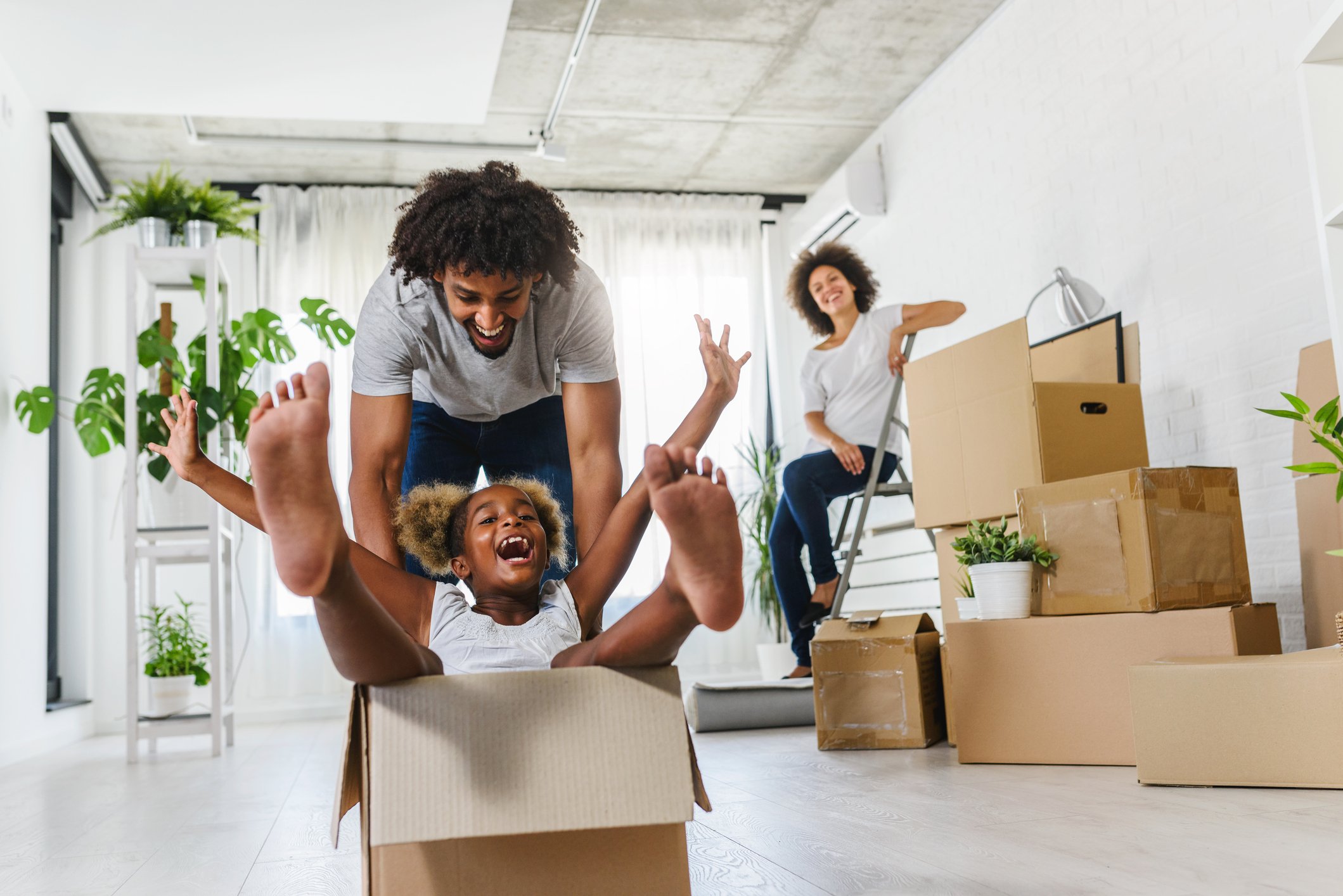 A man, woman, and child having fun amidst empty boxes.