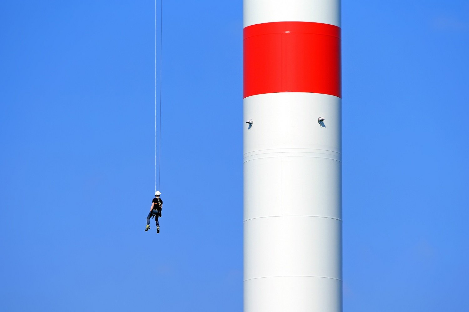 Worker suspended from a cable on a wind turbine.