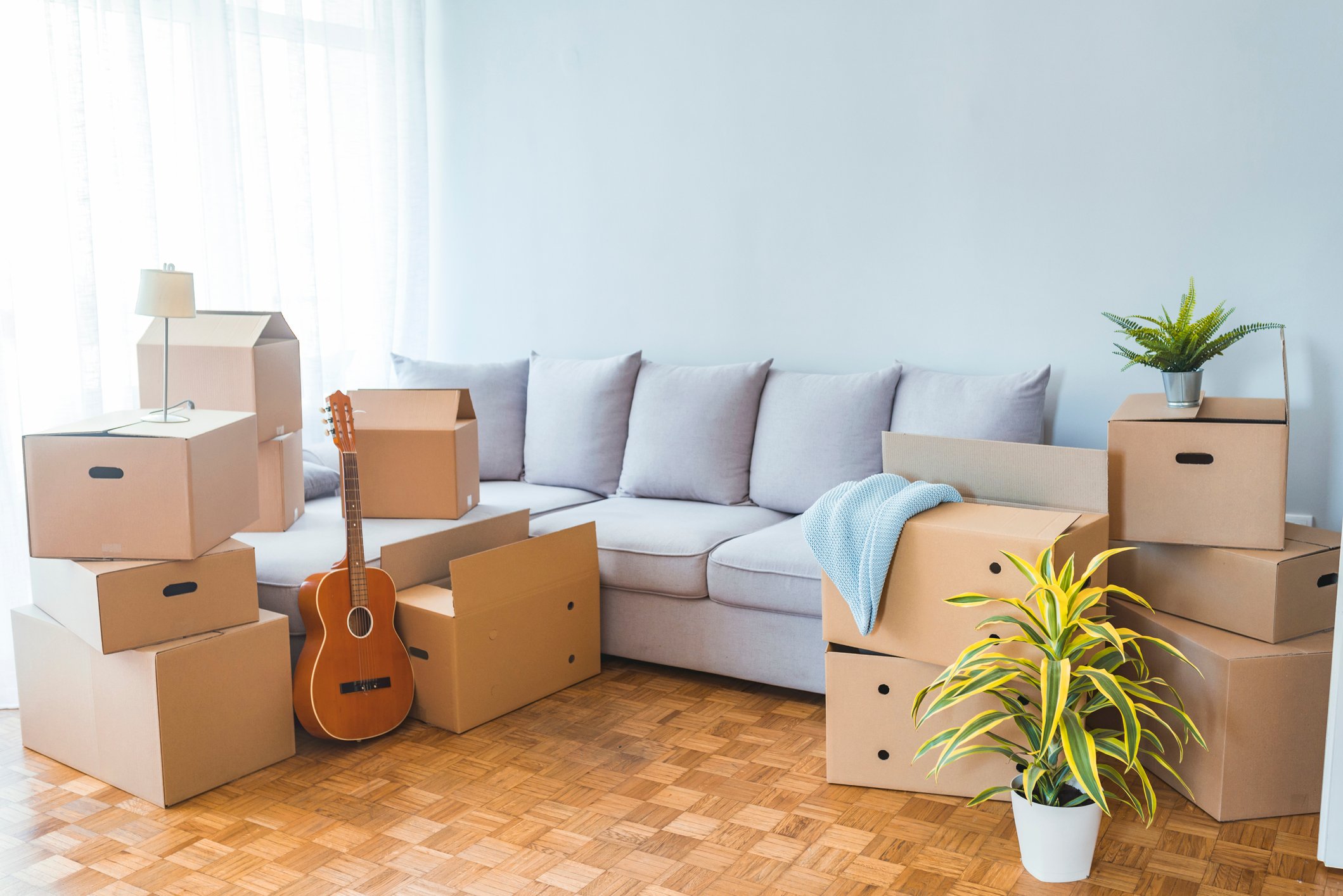 A brightly lit living room with moving boxes and a sofa.