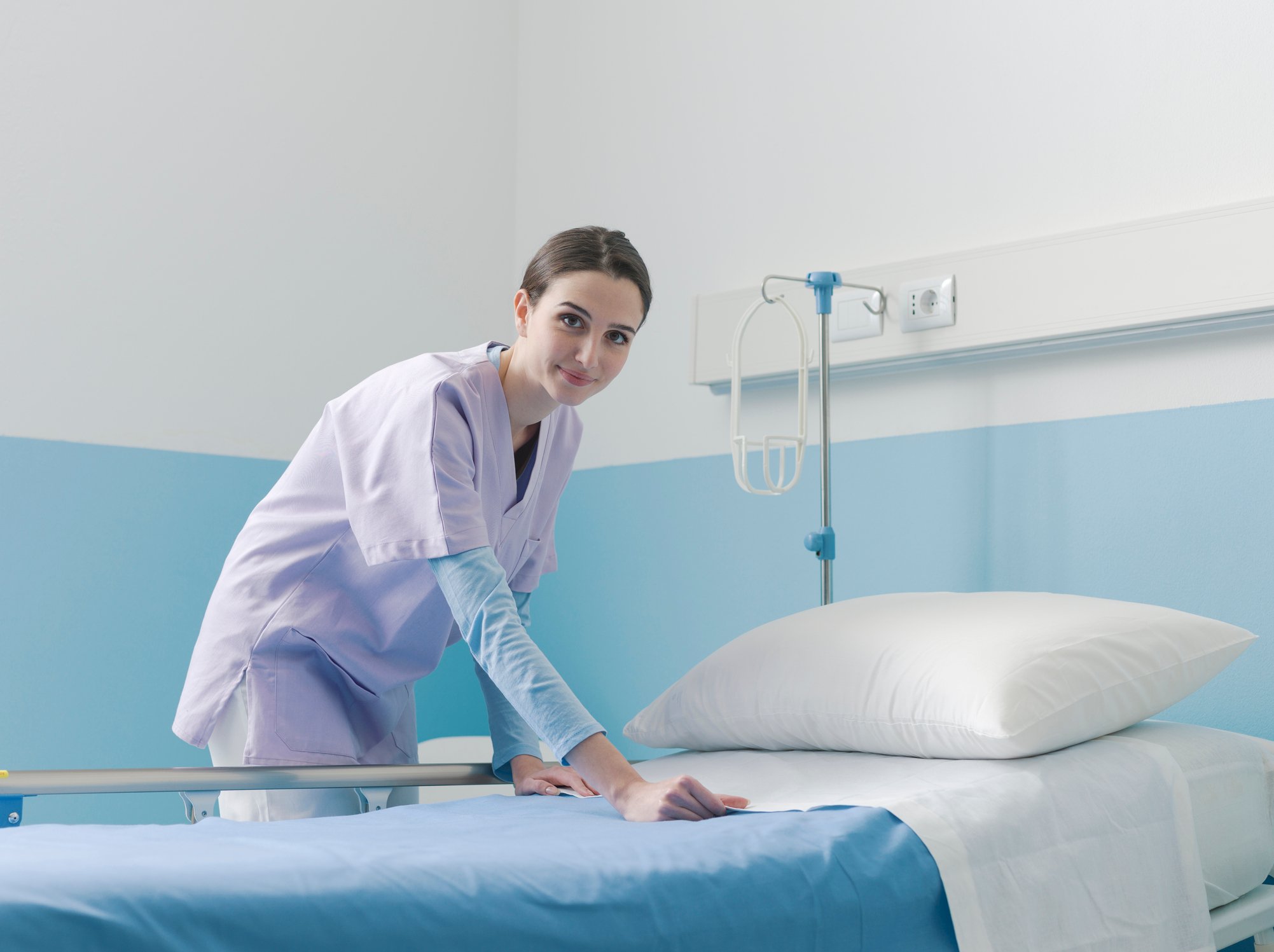 A nurse making up a hospital bed