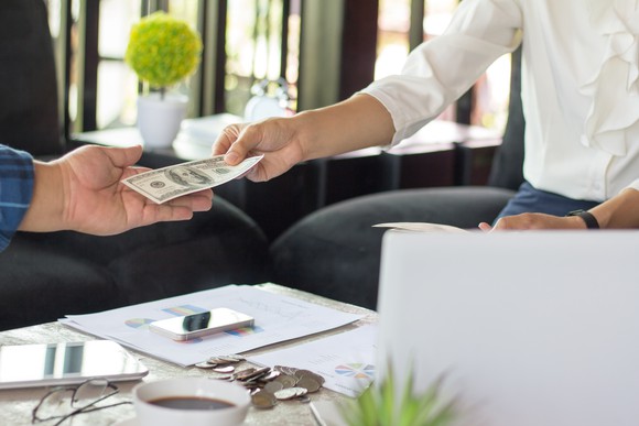 A man passing a hundred dollar bill to another man