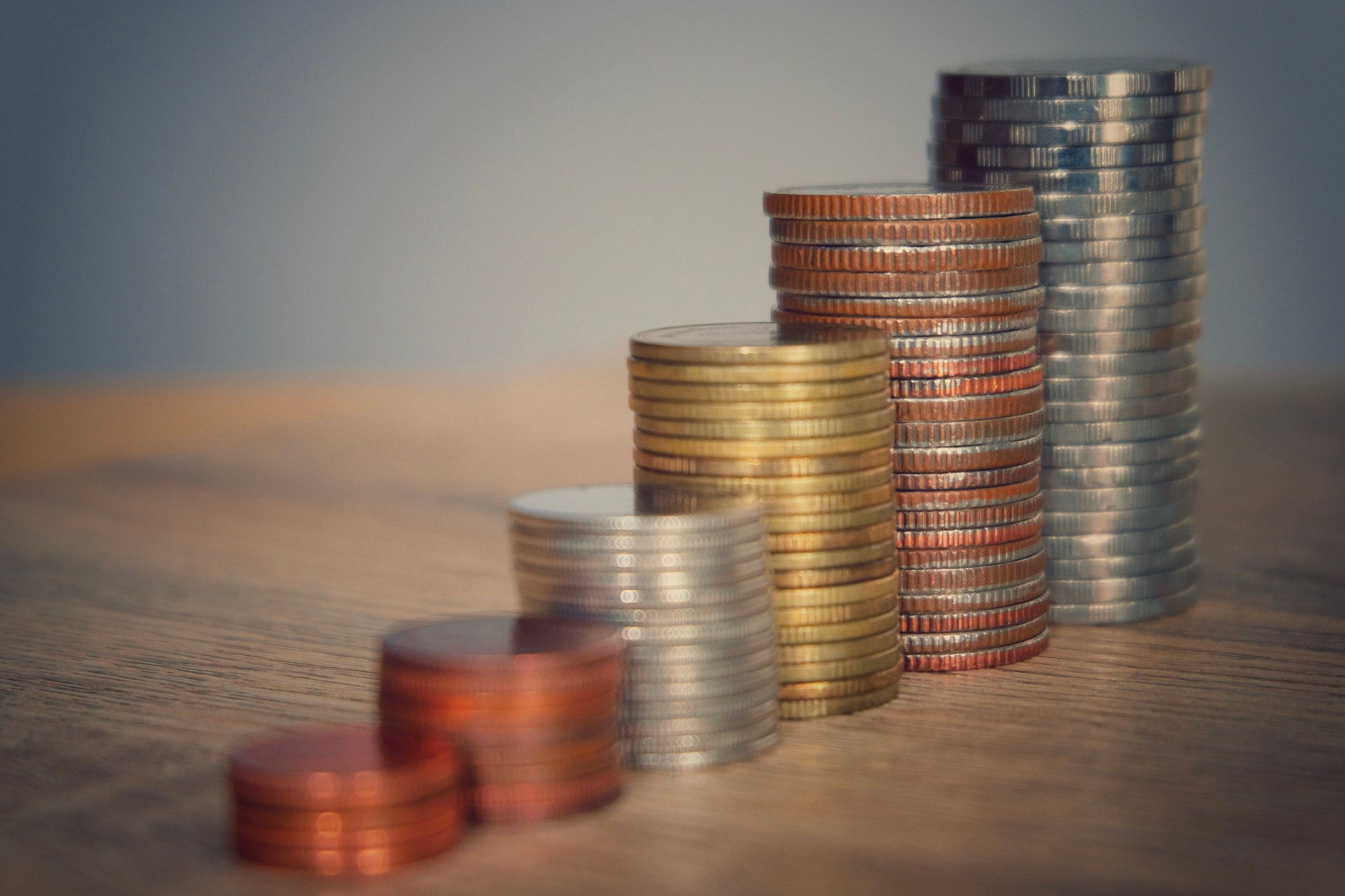 Stacked coins on a wooden table. 