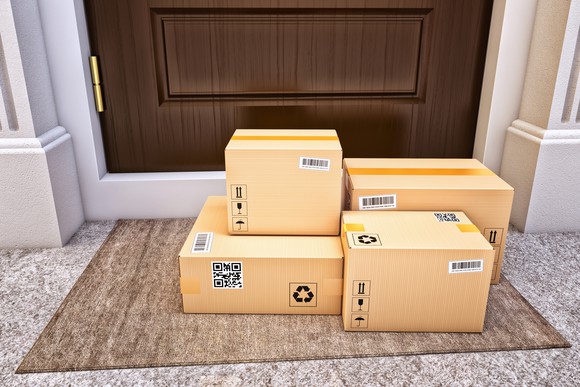 A group of boxed parcels sit on a doorstep. 