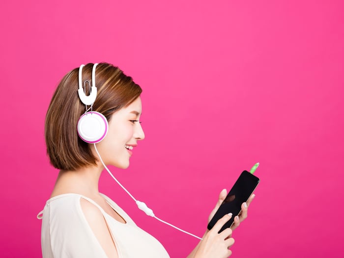 A young woman listens to music on her phone.