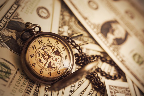 A pocket watch on scattered dollar bills