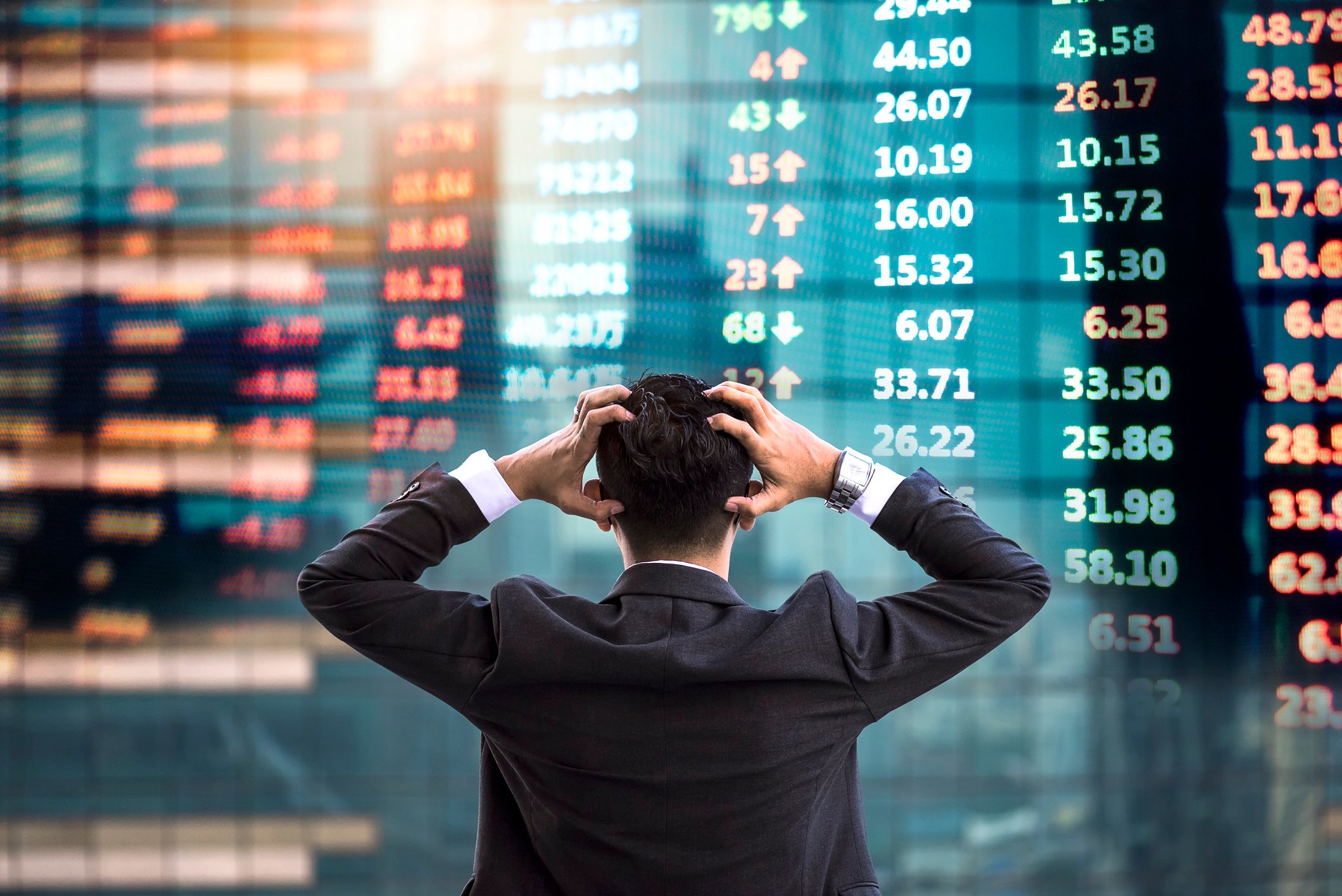 A frustrated investor looks at a wall of stock tickers.
