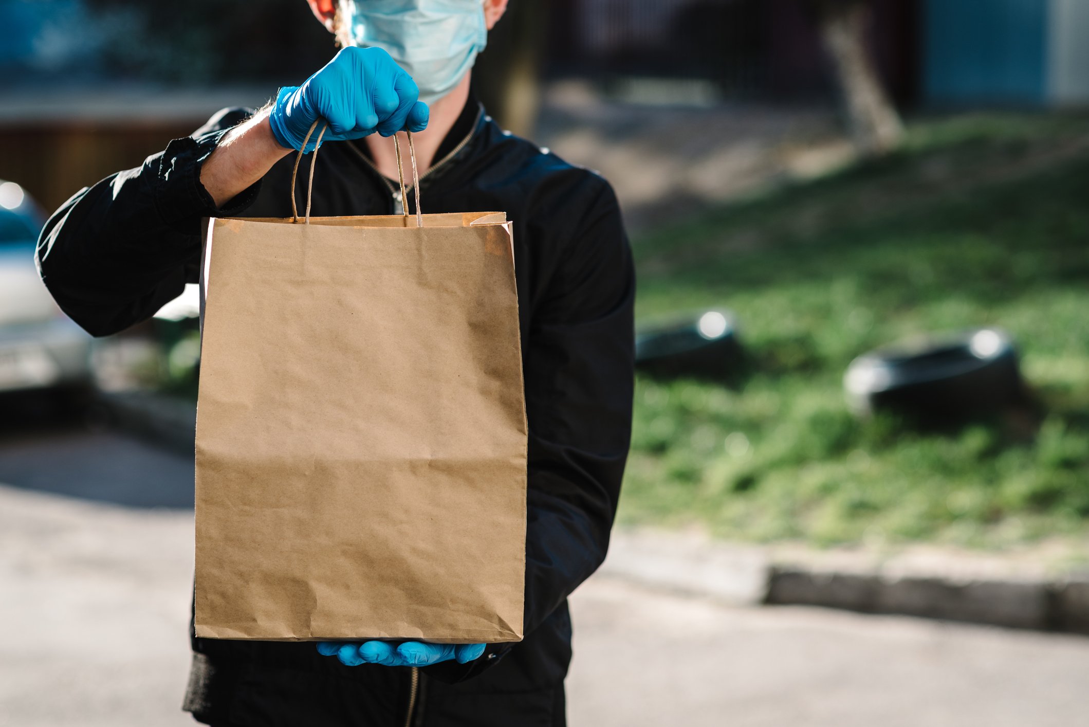 A man wearing a mask and gloves making a food delivery