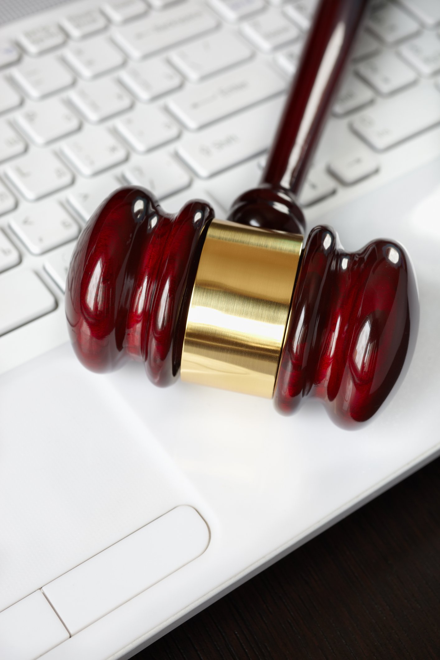 A judge's gavel rests on a laptop keyboard.