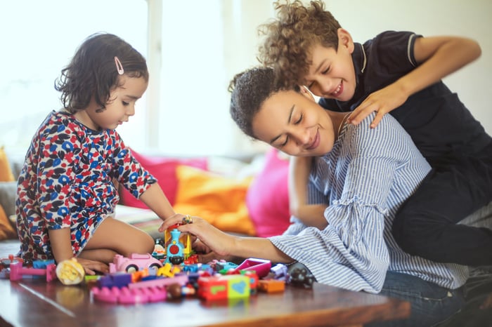 Kids climbing on mom while playing with toys
