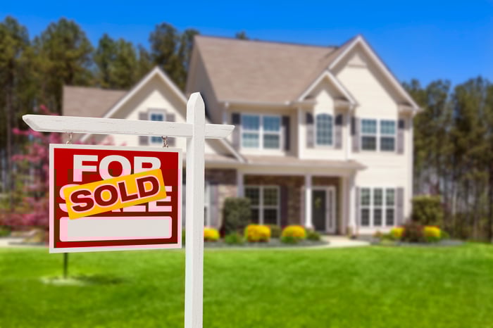 SOLD sign on the lawn of a house.