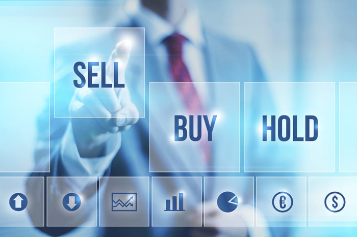 A businessperson in a suit pressing the sell button on a digital screen. 