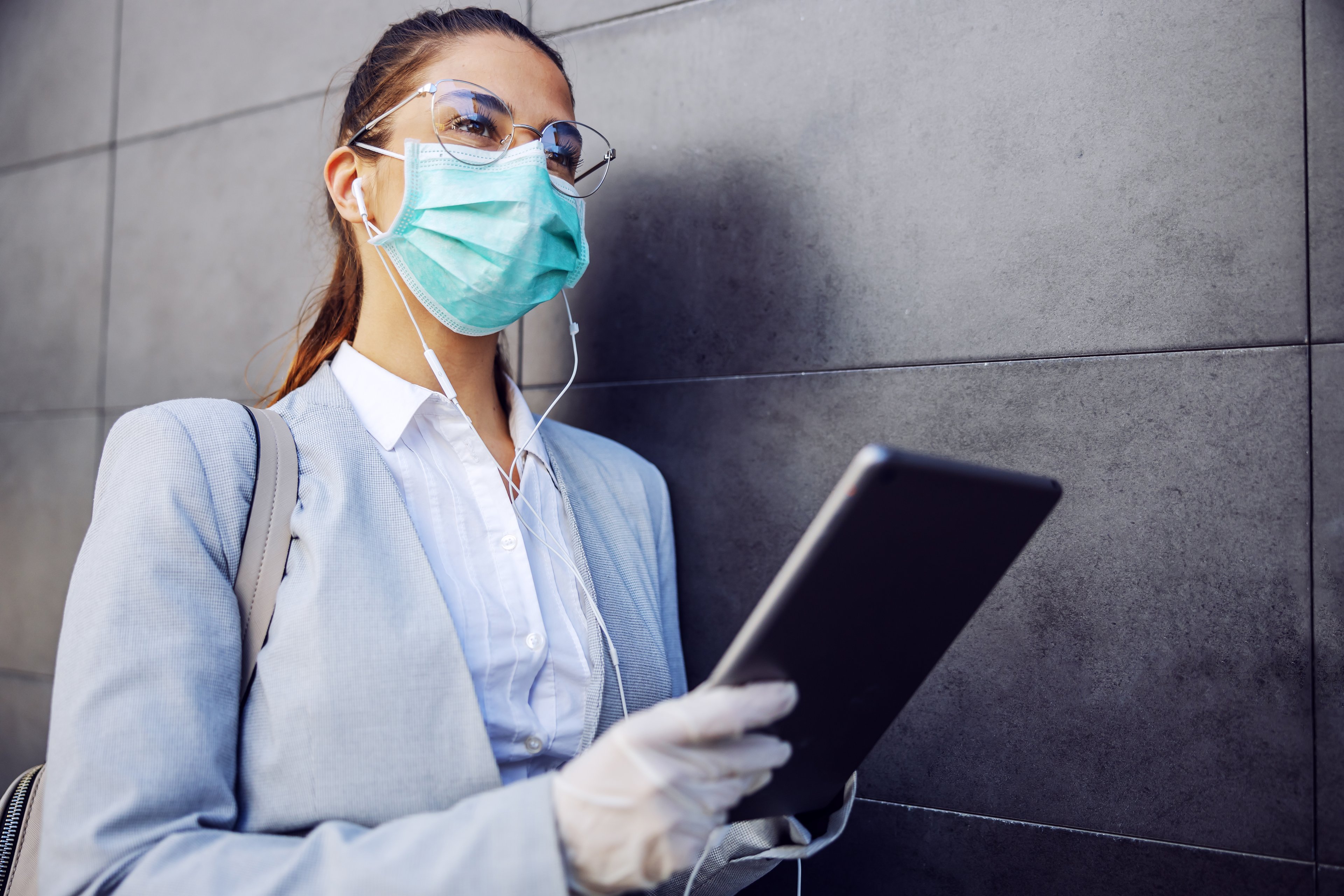 Businesswoman using tablet while wearing mask and gloves.