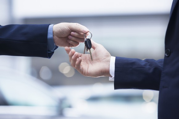Closeup of one hand handing car keys to another. 