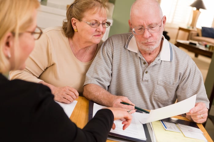 Older couple reviewing financial paperwork with advisor.