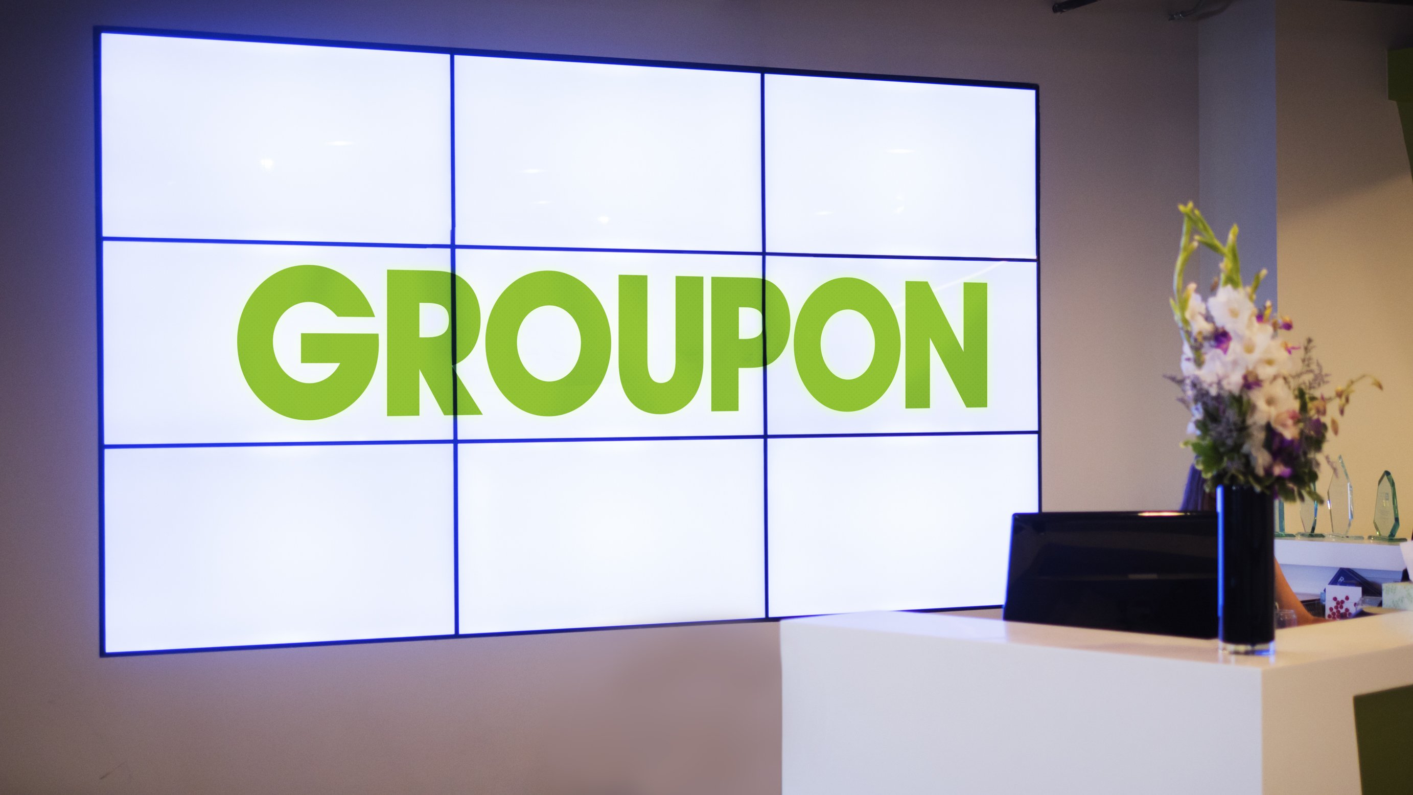 Nine TV screens spelling out Groupon at its corporate office reception desk.