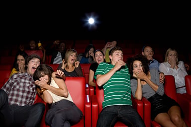 Audience in a movie theater reacts with fear