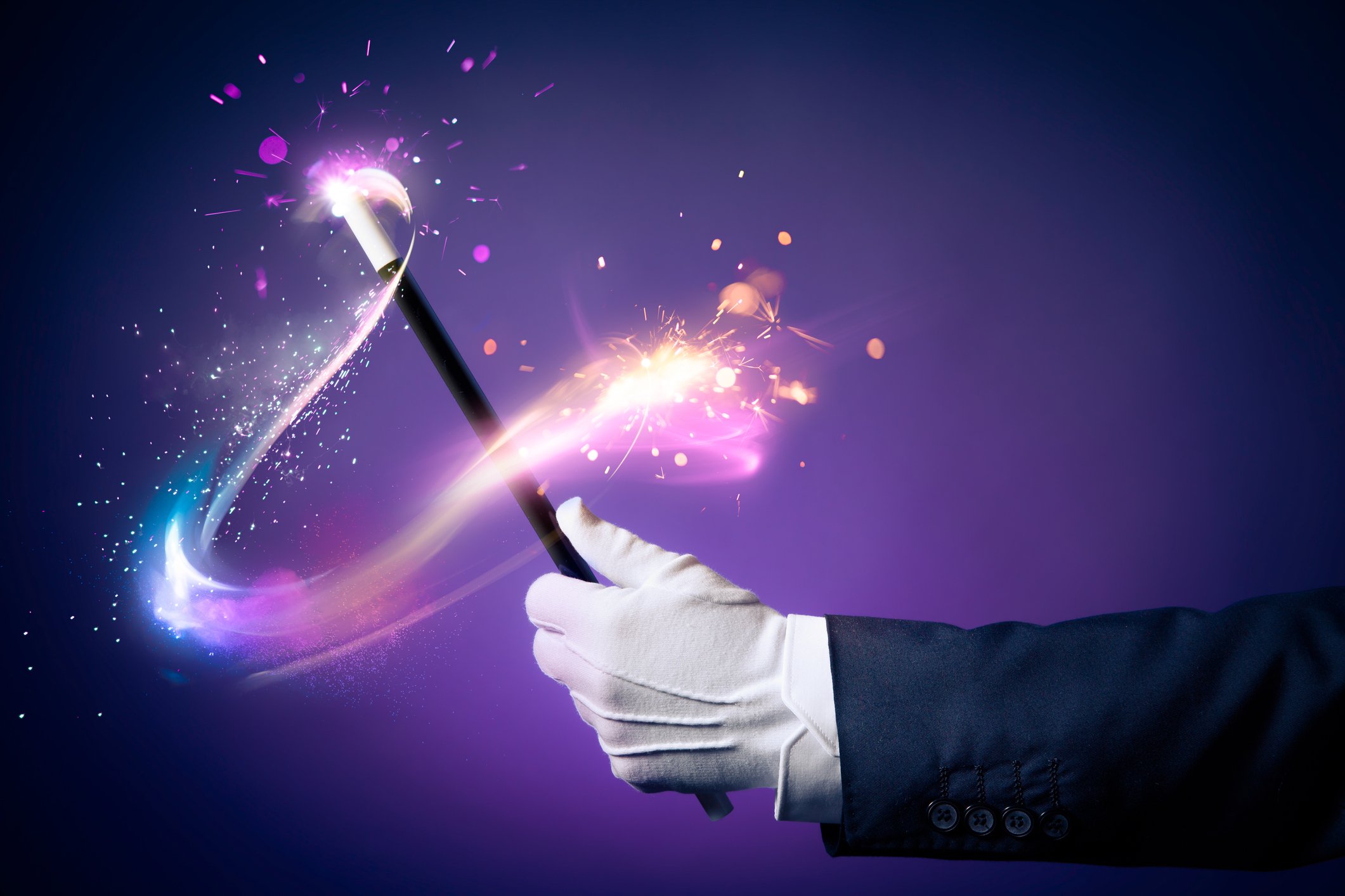A white-gloved hand is waving a wand, leaving a trail of pixie dust.