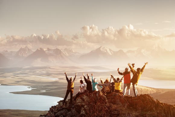 A group of people celebrating on a mountain peak.